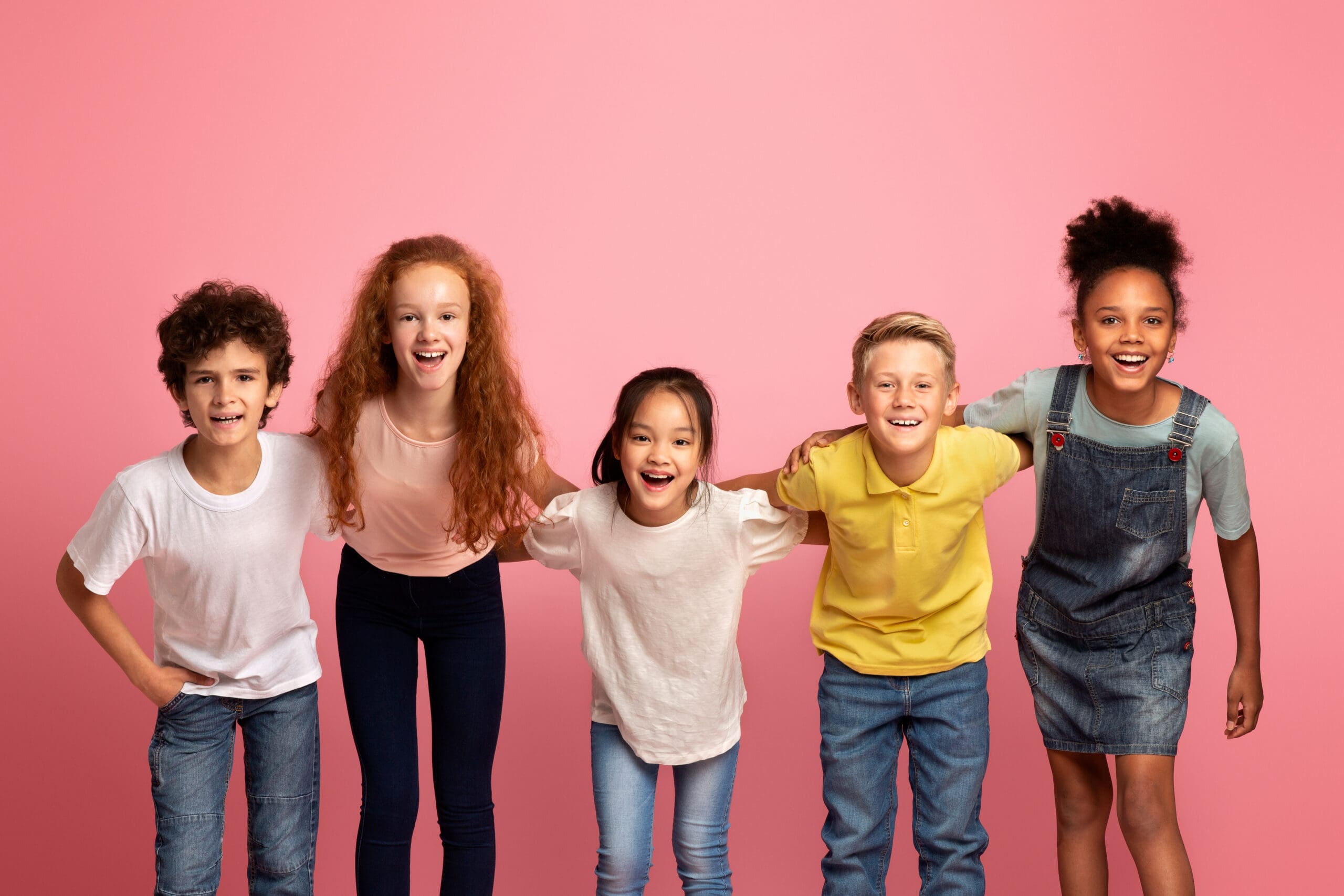 Portrait of multiethnic schoolkids smiling on pink background
